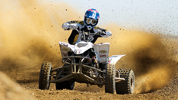 A four-wheel atv making dust on a dirt track.