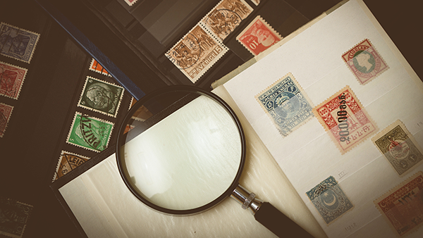 Collectible postage stamps with a magnifying glass.