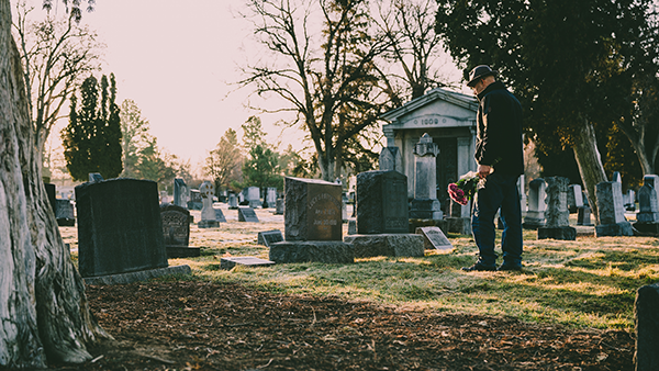 A man holding flowers in a cemetery.