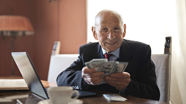 A man is wearing a suit and holding cash in his hand.