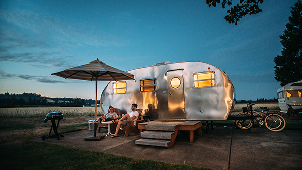 A couple sitting in front of a travel trailer