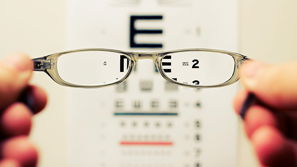 Glasses being held in front of an eye chart