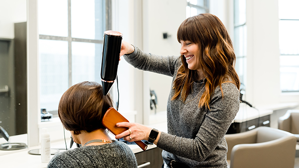 A beautician doing a client's hair in a salon.