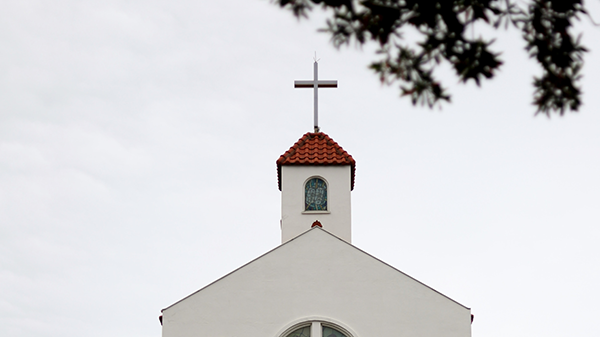 The top of a church buildng with a cross on top.