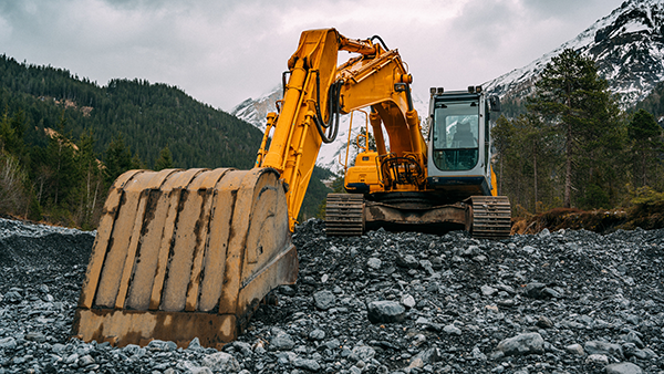 An excavator with mountains in the background.