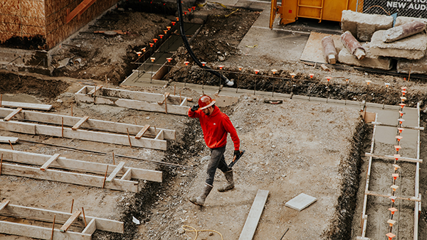 A worker with a hard hat walking on a construction site.