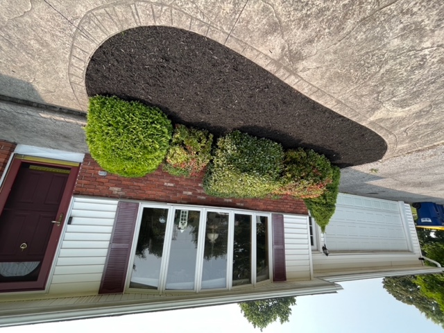 A stamped concrete patio next to a front door. There is also a landscaped garden bed.